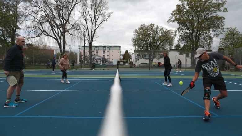 People lineup to play pickleball on an outdoor court. 