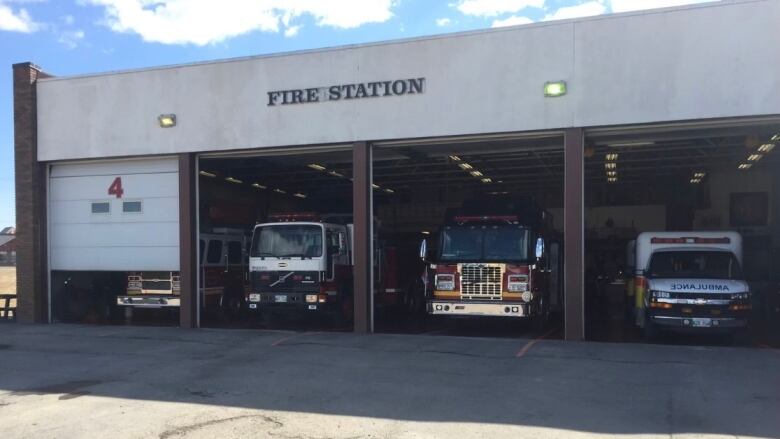 A building with 4 large openings and trucks in each. 