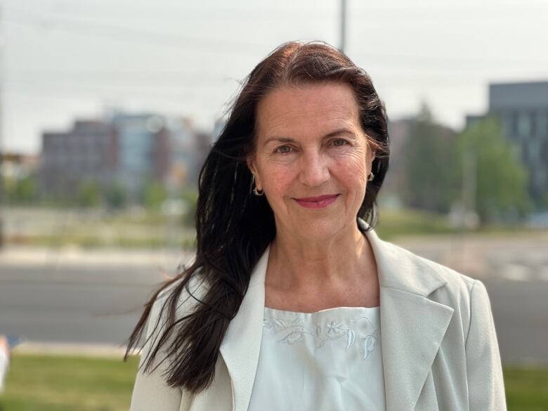 Rosemary McConkey smiles at the photographer standing in from of Durham College.