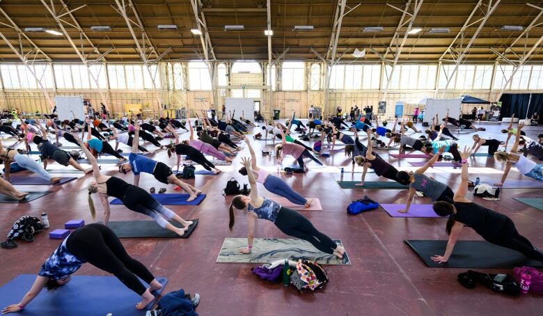 People doing yoga fill an indoor pavilion.