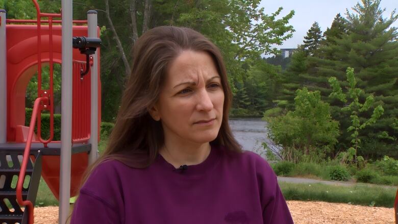 A woman looks worried, standing in a park