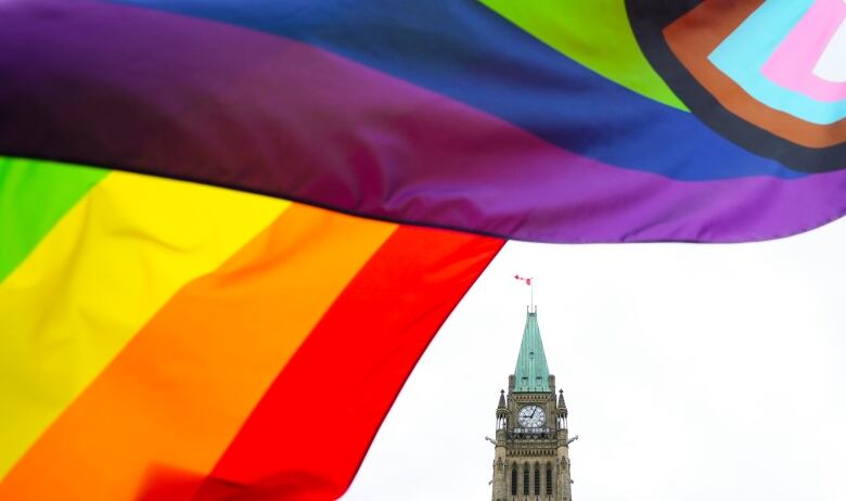 A rainbow Pride flag flies in front of a legislature.