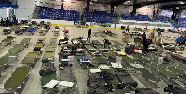 An arena with mostly empty folding cots.