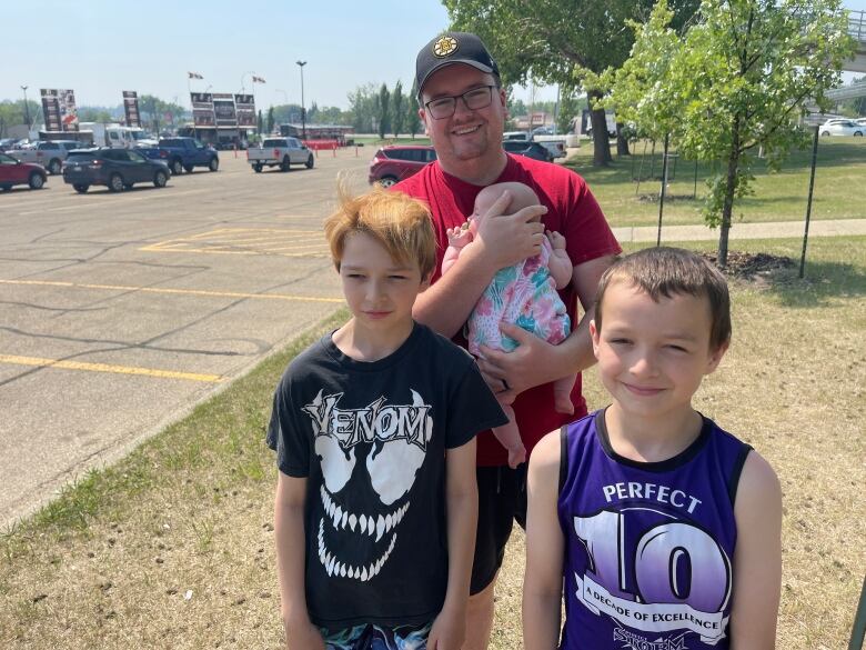 A man stands with his baby and two sons.