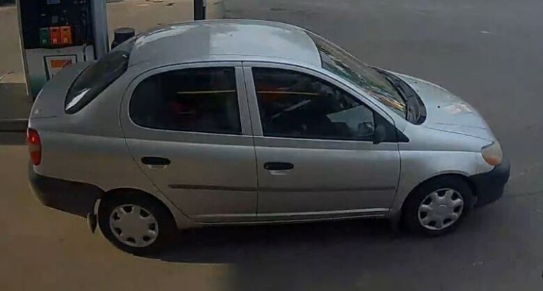 A silver Toyota Echo parked in front of a gas station pump. 