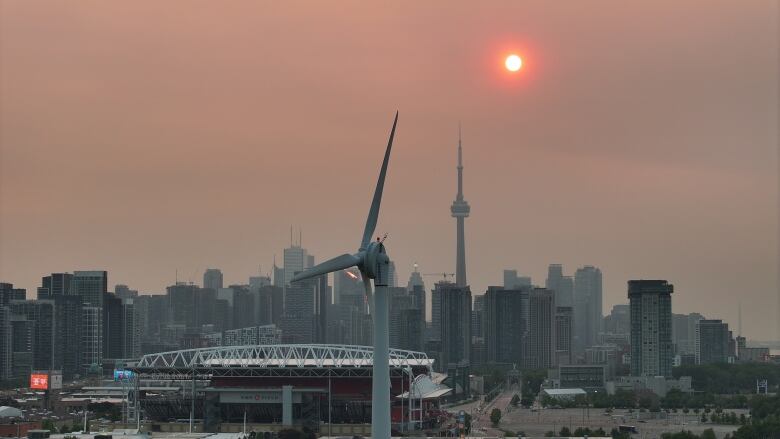 Smog and soot lingers over Toronto at sunrise due to smoke from forest fires.