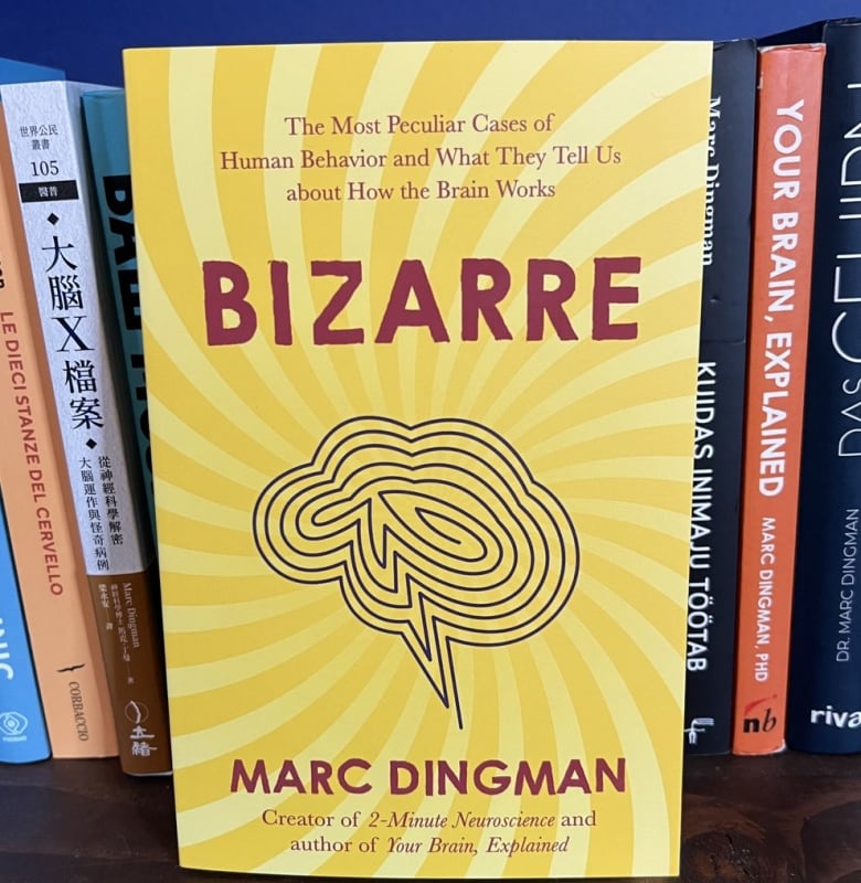 A book in a yellow jacket with an illustration of the brain is seen on a bookshelf 