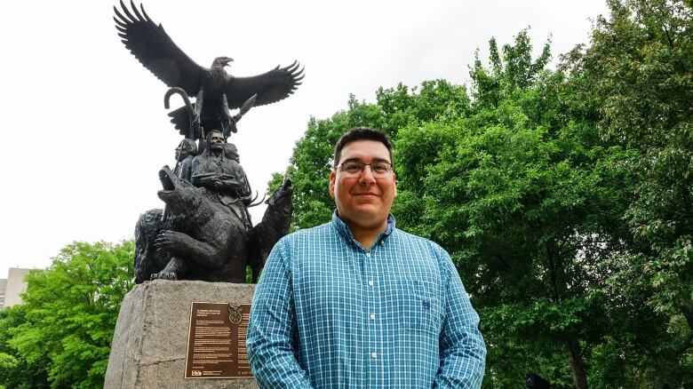 A First Nations chief poses in front of an Indigenous veterans memorial.