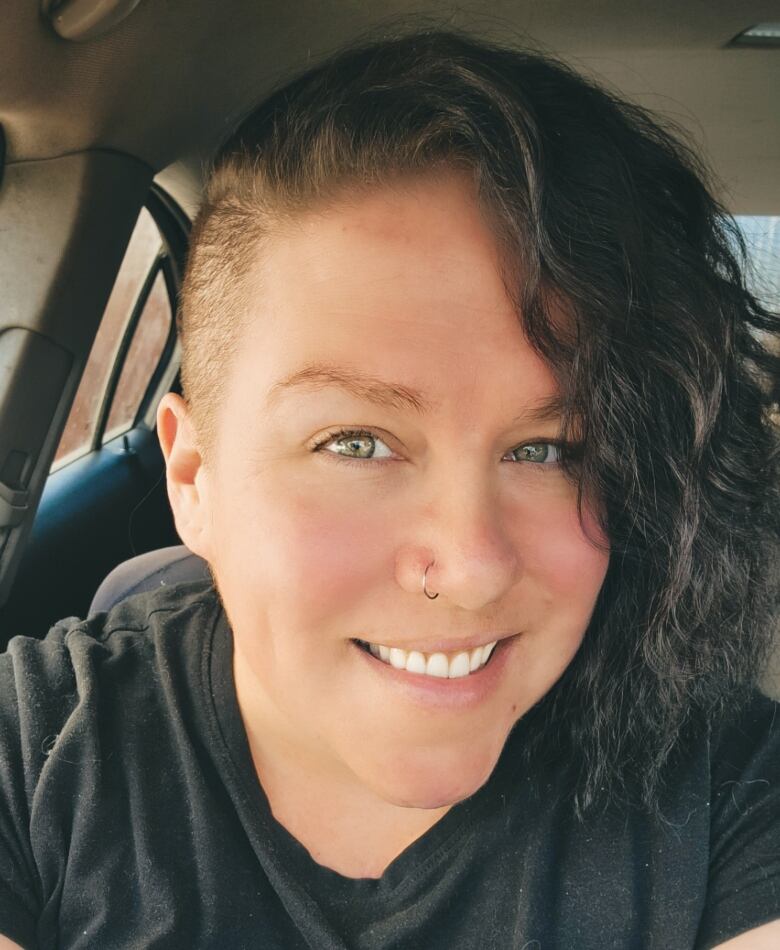 An Indigenous women poses for a selfie and flashes white teeth and a nose ring. 