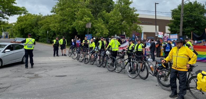 A line of police stand with bikes.