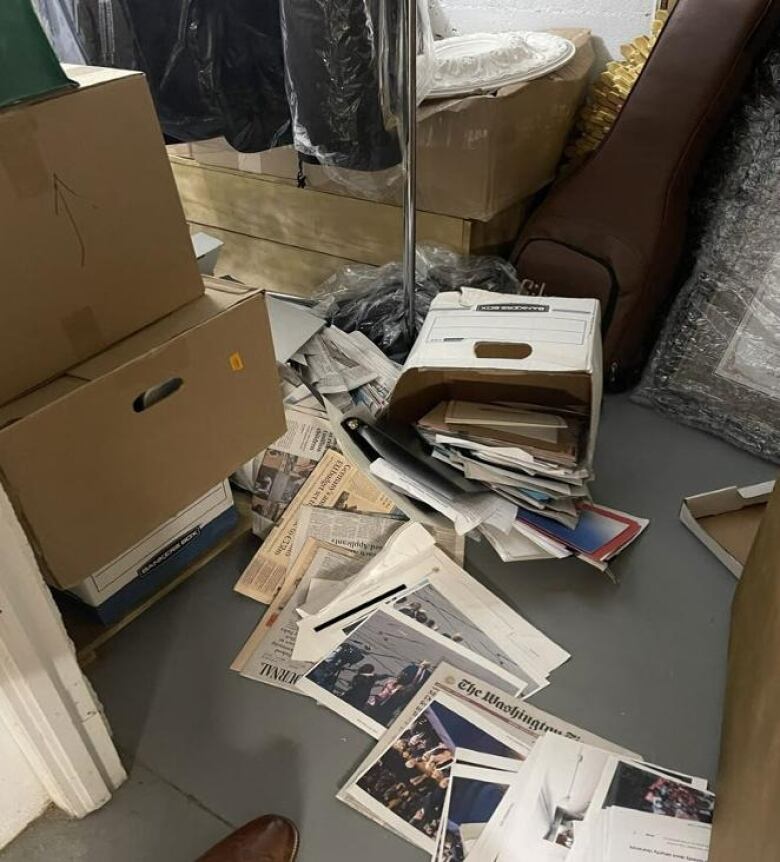 Papers strewn on floor, protruding from a stack of boxes. 