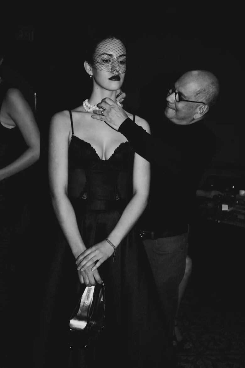 Designer puts jewelry on model.