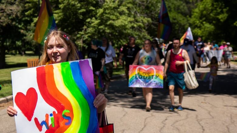 A person holds a poster with a rainbow on it. 