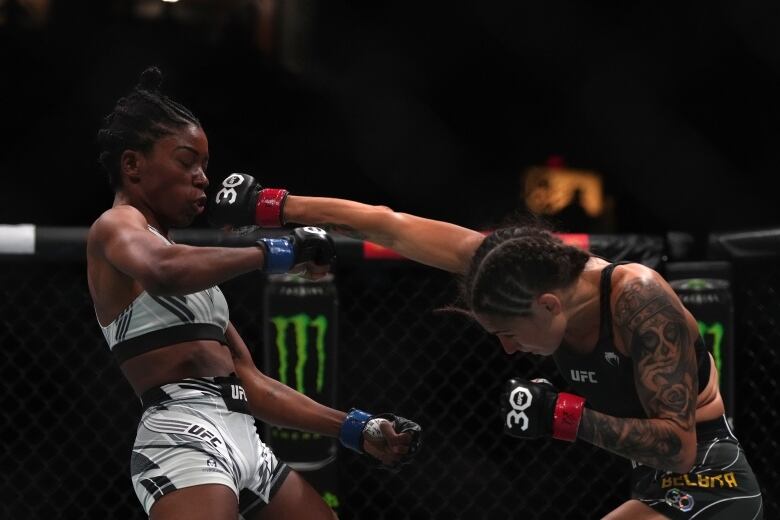 Two women hit each other while in an MMA cage.