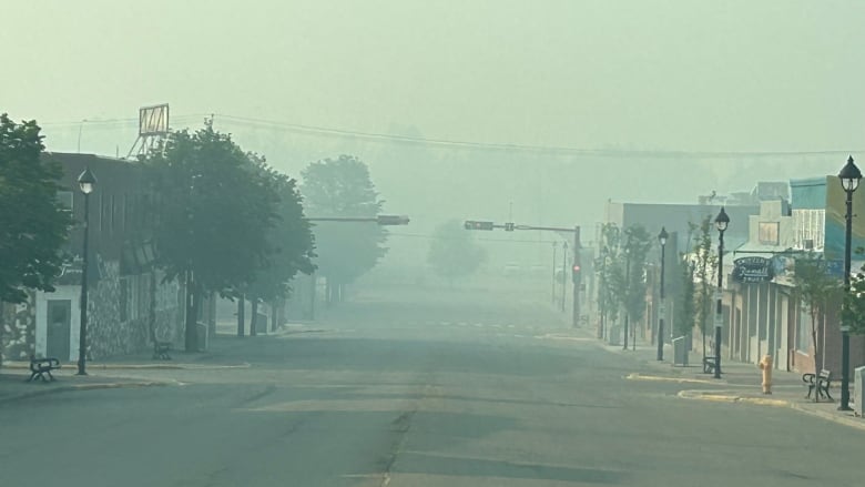 Smoke hangs over an empty street with businesses on either side. 