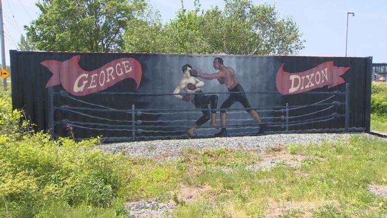 A large, hand-painted mural of two men boxing. It reads, 'George Dixon' in red banners.  George Dixon is punching is opponent in the face. 