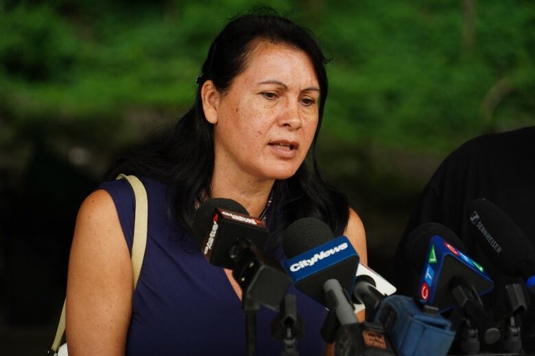 Na'kuset, executive director of the Native Women's Shelter of Montreal speaks into several microphones at a news conference.  