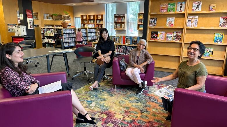 Four women sit in a circle speaking with each other. 