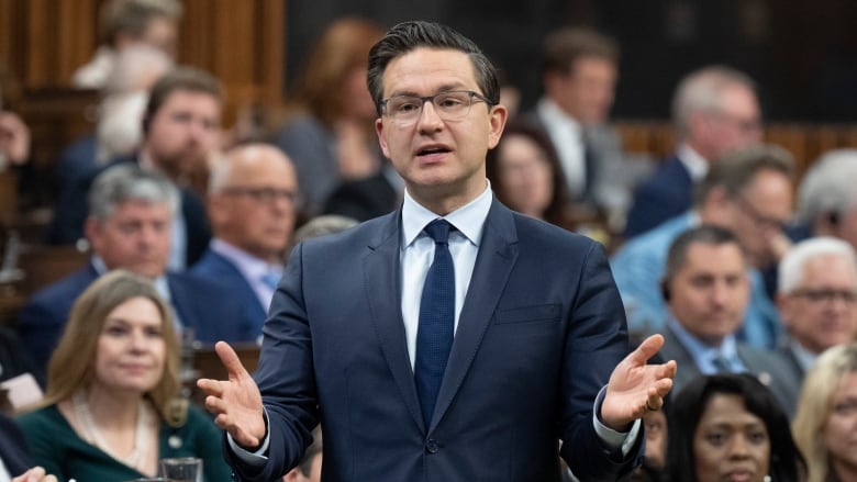 A man in a blue suit stands in the House of Commons.