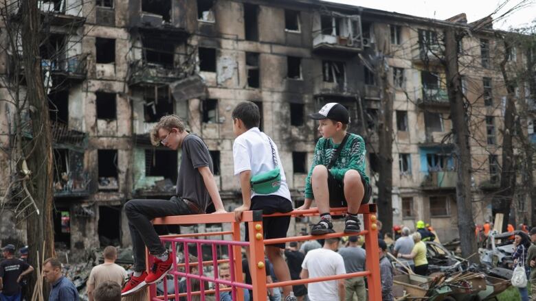 Children look at a bombed-out building.