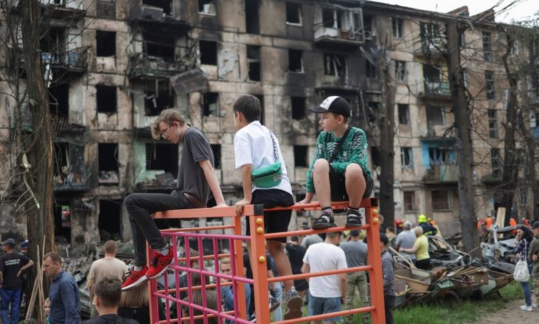 Children look at a bombed-out building.