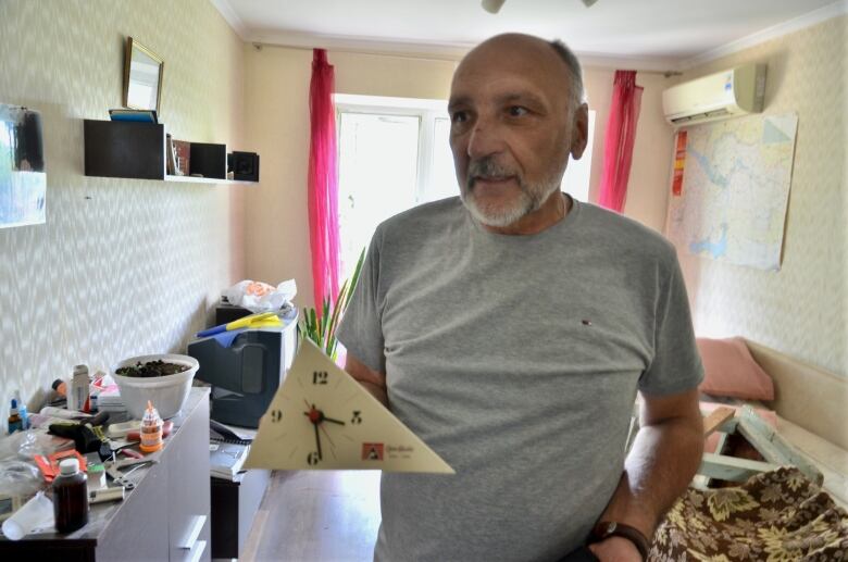 A man holds a broken clock.