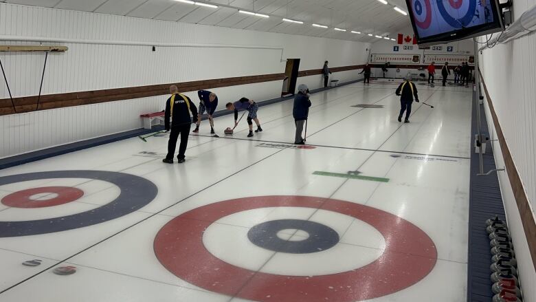 Two-sheet curling rink with people playing.