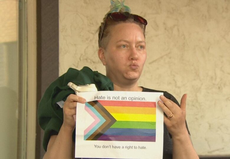 A woman holds up a sign reading 