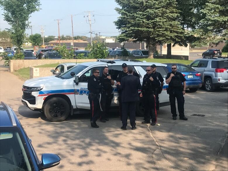 Police officers stand by a cruiser outside.