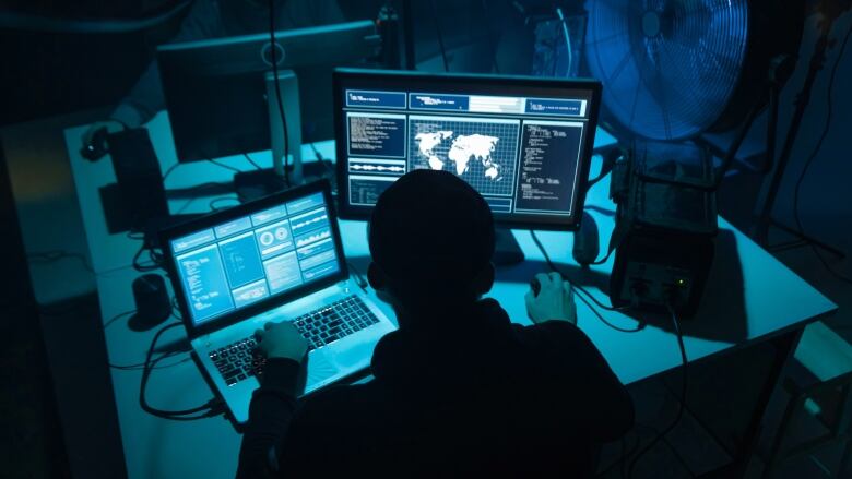 A man sits in the dark working on a computer.