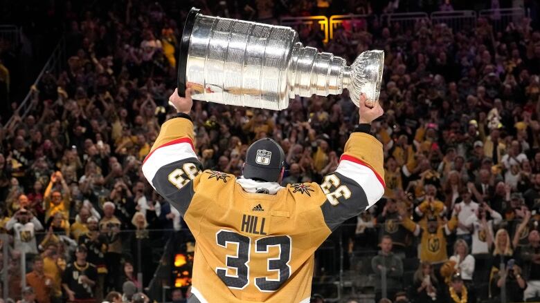 A hockey player lifts the Stanley Cup.