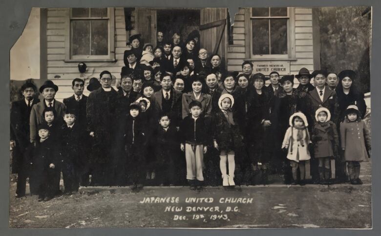 A group of people stand in front of a wooden building.