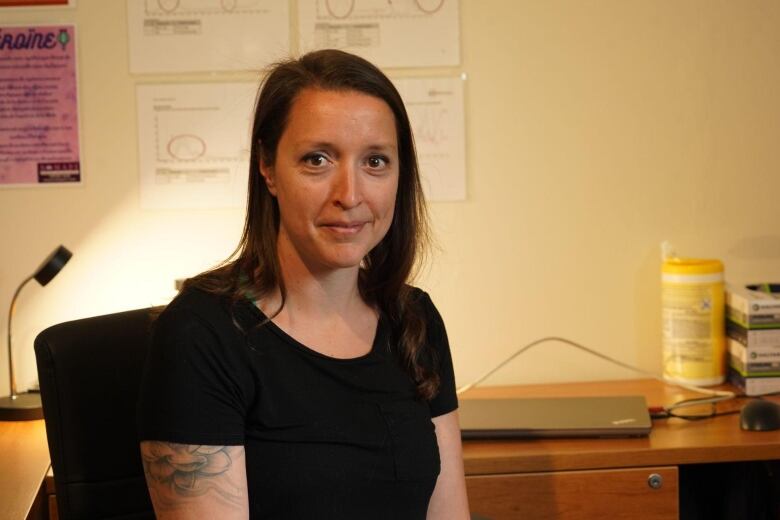 A woman in an office looks into the camera and smiles. 