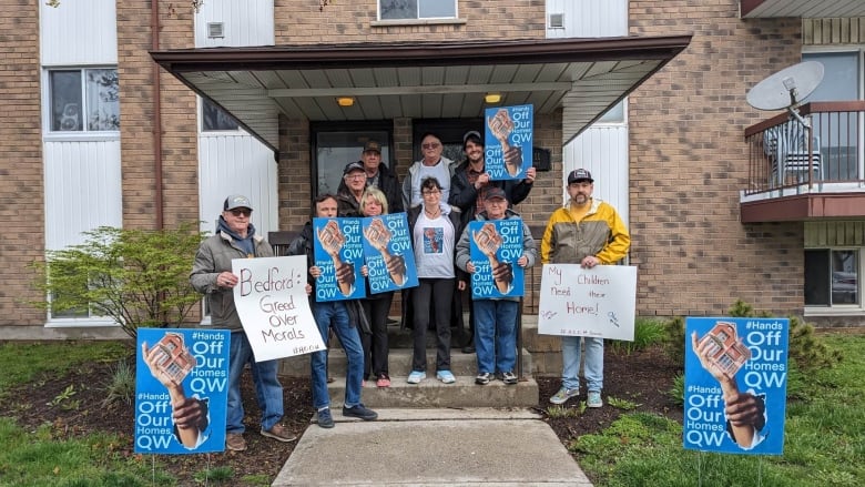 Renters pose for a photograph outside their apartment building.