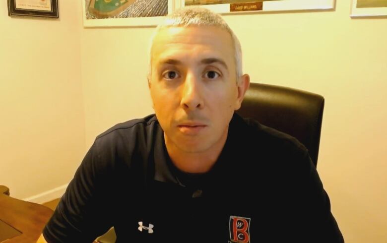 A white man with blond hair sits in an office.