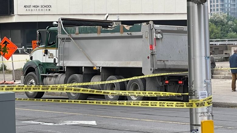 A dump truck sits behind police tape.