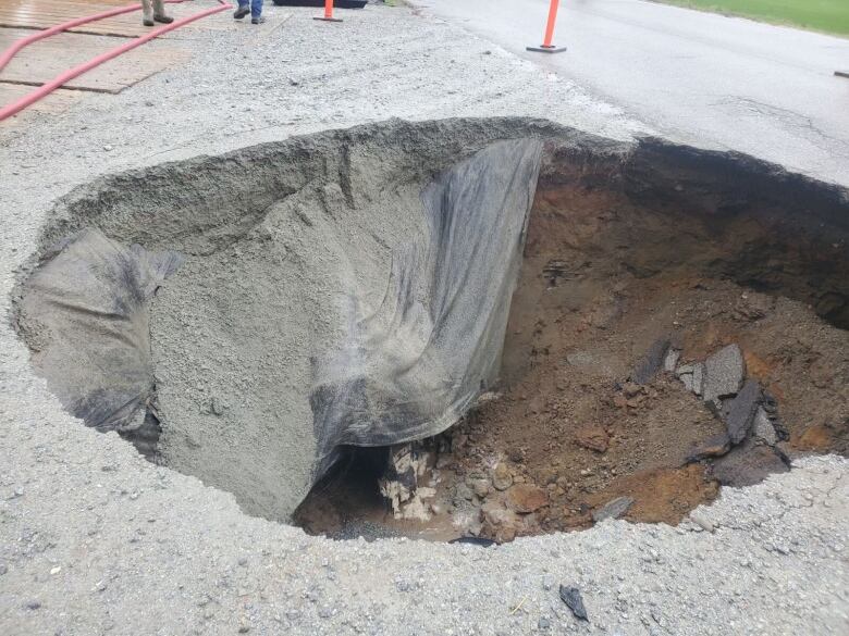 A closeup of a sinkhole in a paved area.