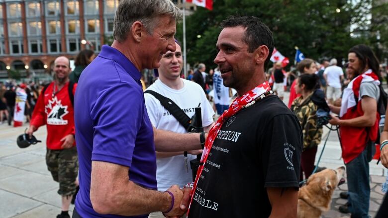 Two men shake hands.