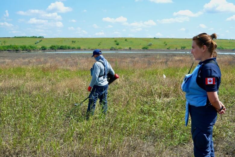 Two people stand in an open field.