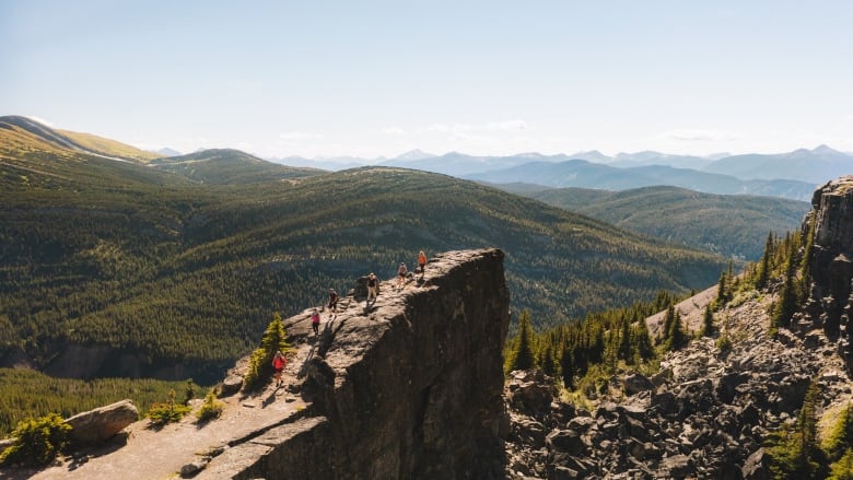 Hikers make their way to the top of a mountainous outcrop. 