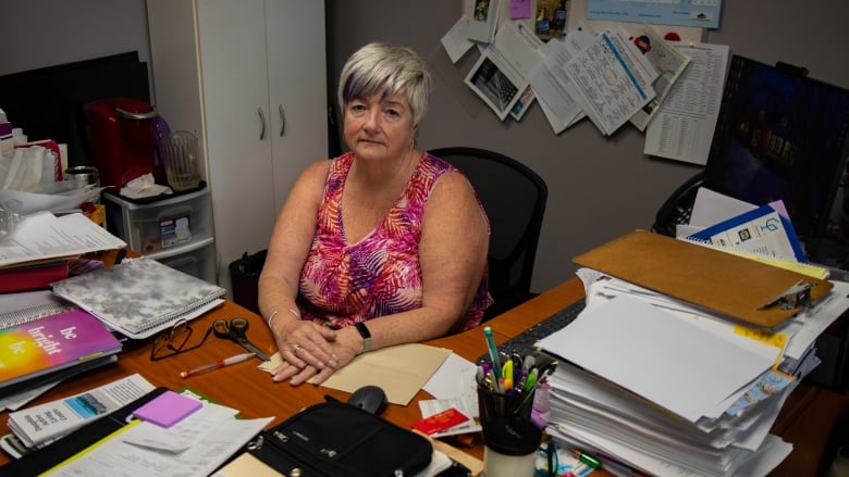 A woman sits behind a desk in an office.