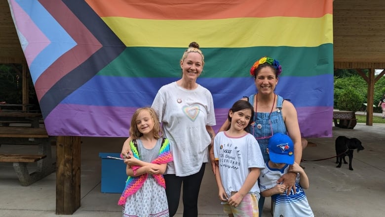 A woman stands next to another woman and three kids. 