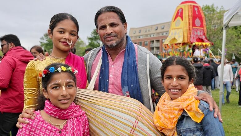 A man is shown smiling with his three daughters