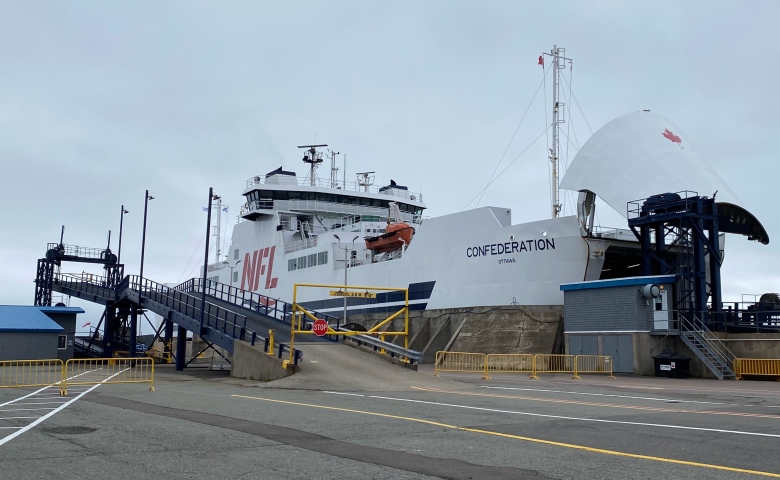 A large passenger and vehicle ferry is shown at dock with its nose cone open to accept vehicles. 