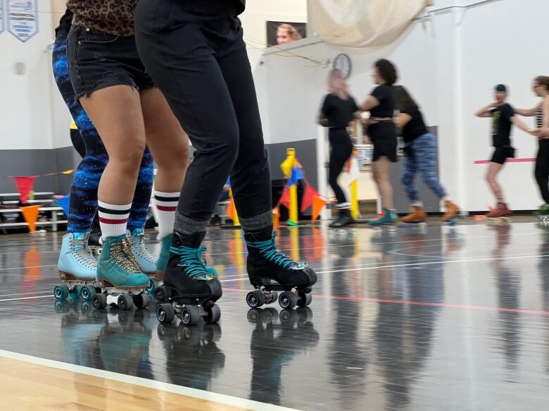 A bunch of skaters wearing colorful roller skates.