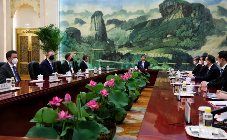 Several people in suits are shown at a large conference table.