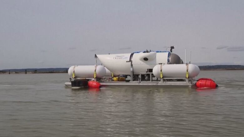 A white vessel with red buoys on the water