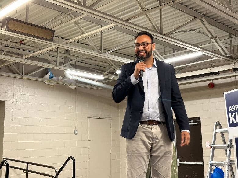 Conservative candidate Arpan Khanna is pictured on a stage at a victory night party.