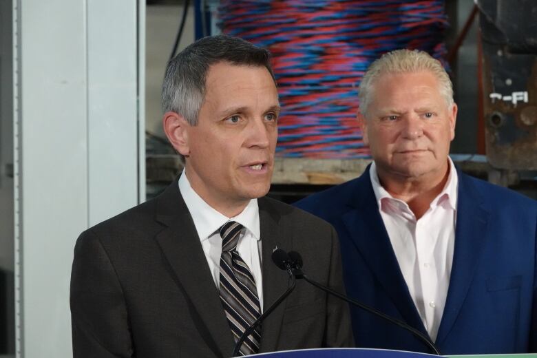 A mayor speaks into a microphone as a provincial leader stands behind him.