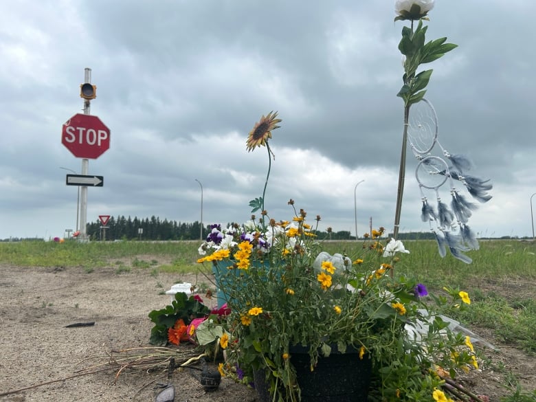 A bouquet of flowers and a dream catcher near a stop sign along the road. 